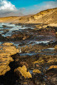 View of rocks in water against cloudy sky
