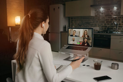 Side view of businesswoman doing video call with colleagues on laptop