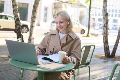 Young woman using laptop at cafe