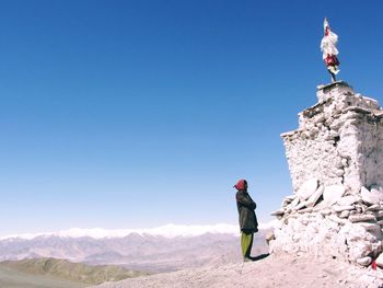 Man standing on mountain against clear blue sky