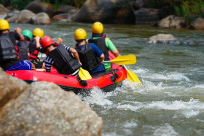 Rear view of people river rafting