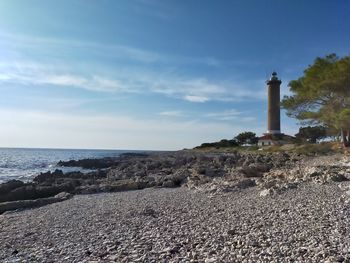 Lighthouse by sea against sky
