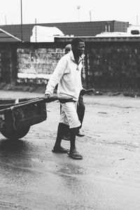 Man pulling cart on road in city