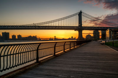 Manhattan bridge over east river against sky during sunrise seen from brooklyn park