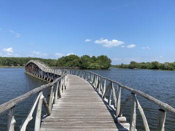 Wooden bridge over calm lake against sky
