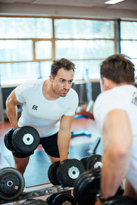 Man lifting dumbbells while exercising in gym