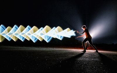 Side view of man standing on road at night