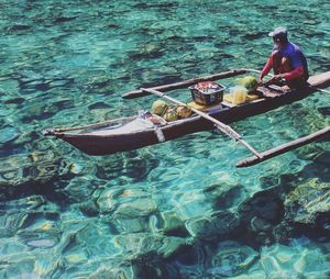 Man with fruits on outrigger boat in sea