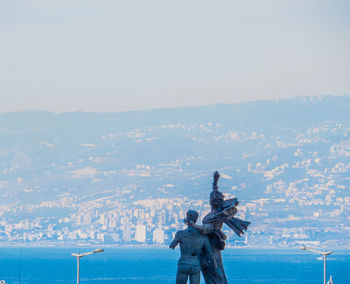 Statue by sea against clear sky