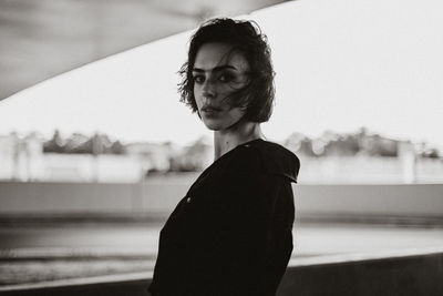 Portrait of young woman standing against blurred background