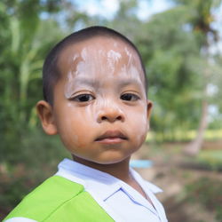 Close-up portrait of cute boy with white powder on face