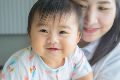 Close-up portrait of smiling baby girl with mother