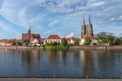 Buildings by river against sky