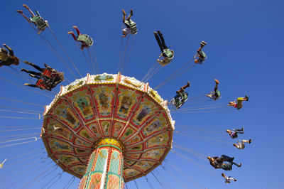 Low angle view of chain swing ride against clear blue sky