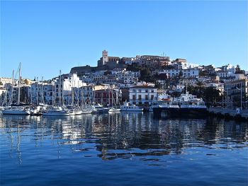 Sailboats in harbor against buildings in city