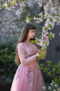 Woman standing by pink flowering plant