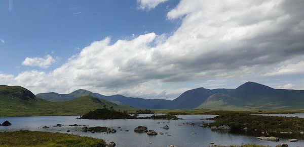 Scenic view of lake by mountains against sky