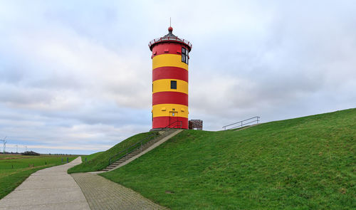 Lighthouse on field against sky