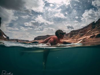 Man swimming in sea against sky