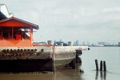 Buildings by river against sky in city