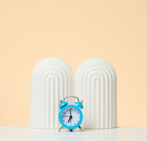 Round alarm clock on a white table. the time is seven in the morning. early rise