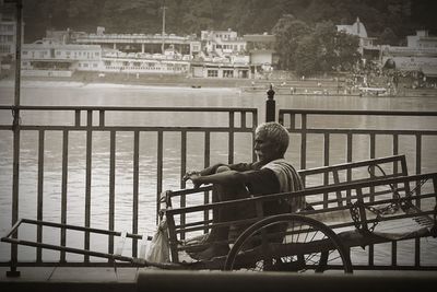 Rear view of man sitting on bridge