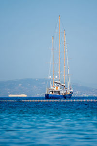 Sailboat sailing on sea against clear blue sky