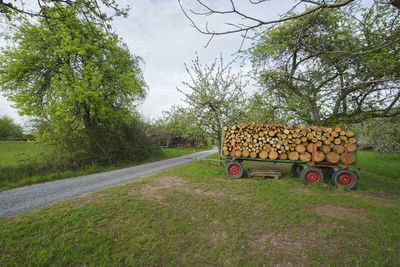 Stack of road by trees on field against sky