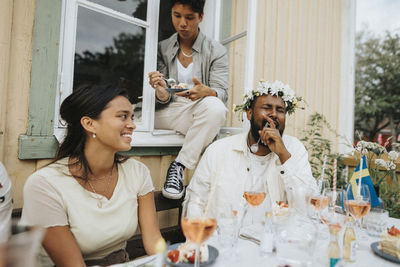 Young man laughing while eating cake with friends during dinner party at cafe