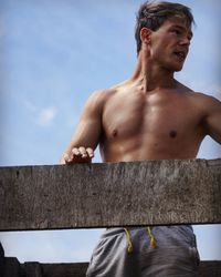 Shirtless handsome man standing by railing