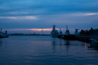 Boats moored at harbor against sky at sunset