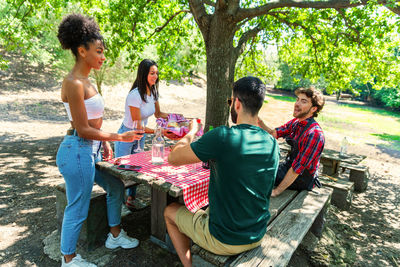 Full length of happy friends sitting on table