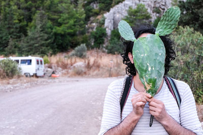 Portrait of man holding cactus plant on road