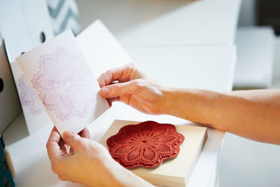 Cropped hands of woman holding paper on table