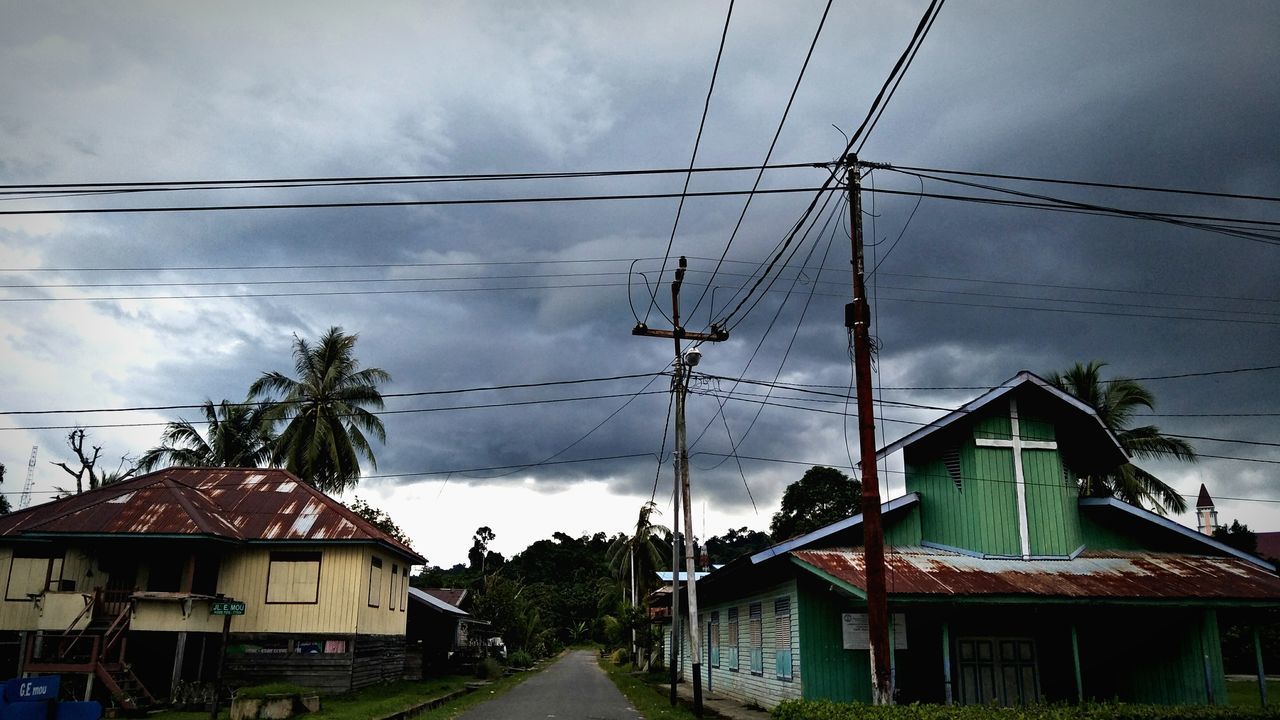 HOUSES AND ELECTRICITY PYLON AGAINST SKY