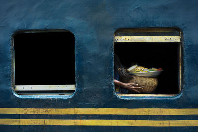 Midsection of person carrying basket with food seen through train window
