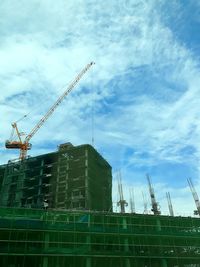 Low angle view of crane at construction site against sky