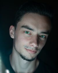 Portrait of smiling man standing against black background