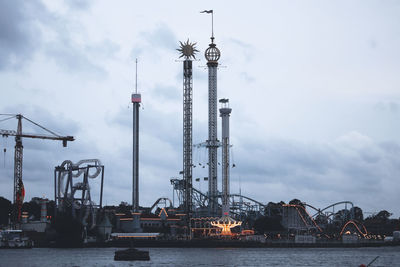 Cranes at riverbank against cloudy sky