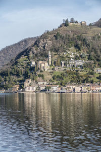 Scenic view of lake by buildings in town against sky