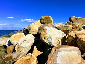 Rock formations by sea against blue sky