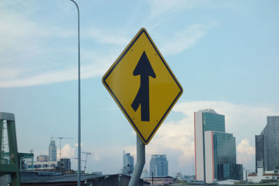 Traffic arrow sign with cityscape in the background