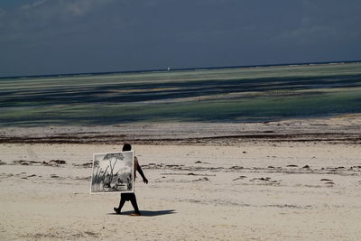 Rear view of person on beach against sky