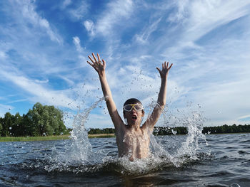 Portrait of young woman with arms raised in water