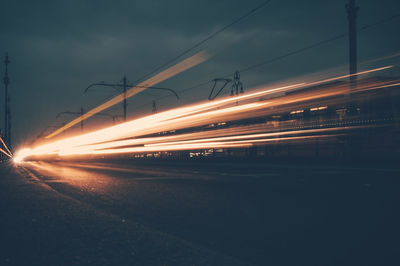 Light trails on road against sky at night