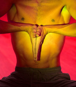 Midsection of shirtless man doing yoga