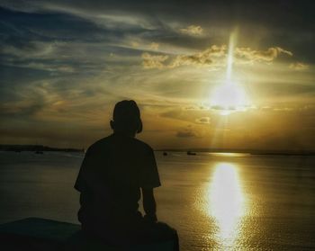 Silhouette man looking at sea against sky during sunset