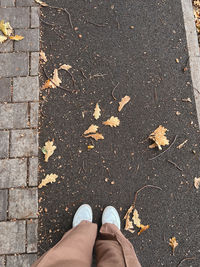 Women's feet in white sneakers are standing on an asphalt 