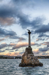 Statue by sea against sky during sunset