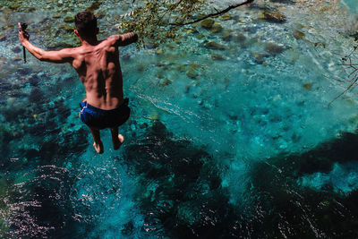 Rear view of shirtless man swimming in sea